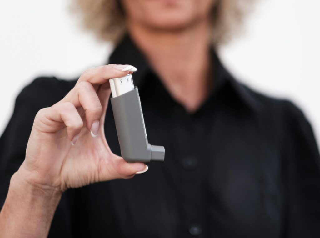 Close-up of a woman holding an asthma inhaler, focusing on respiratory health solutions.