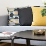 Contemporary living room interior featuring a stylish sofa, decorative pillows, and a vase of flowers.