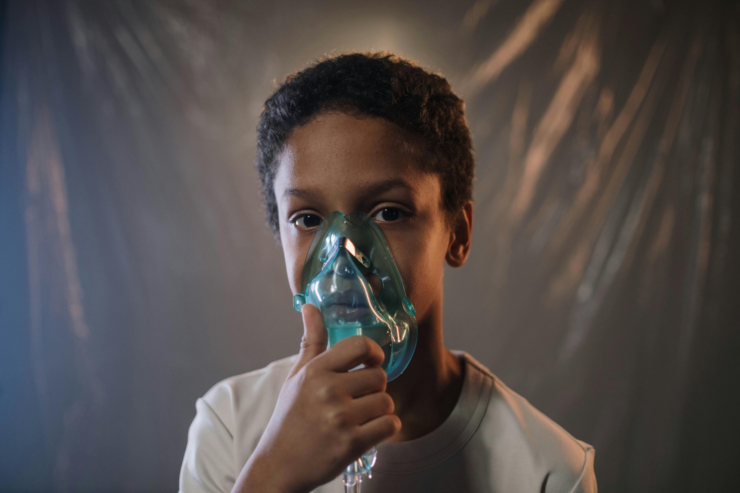 Portrait of a child using an oxygen mask indoors, highlighting health care needs.