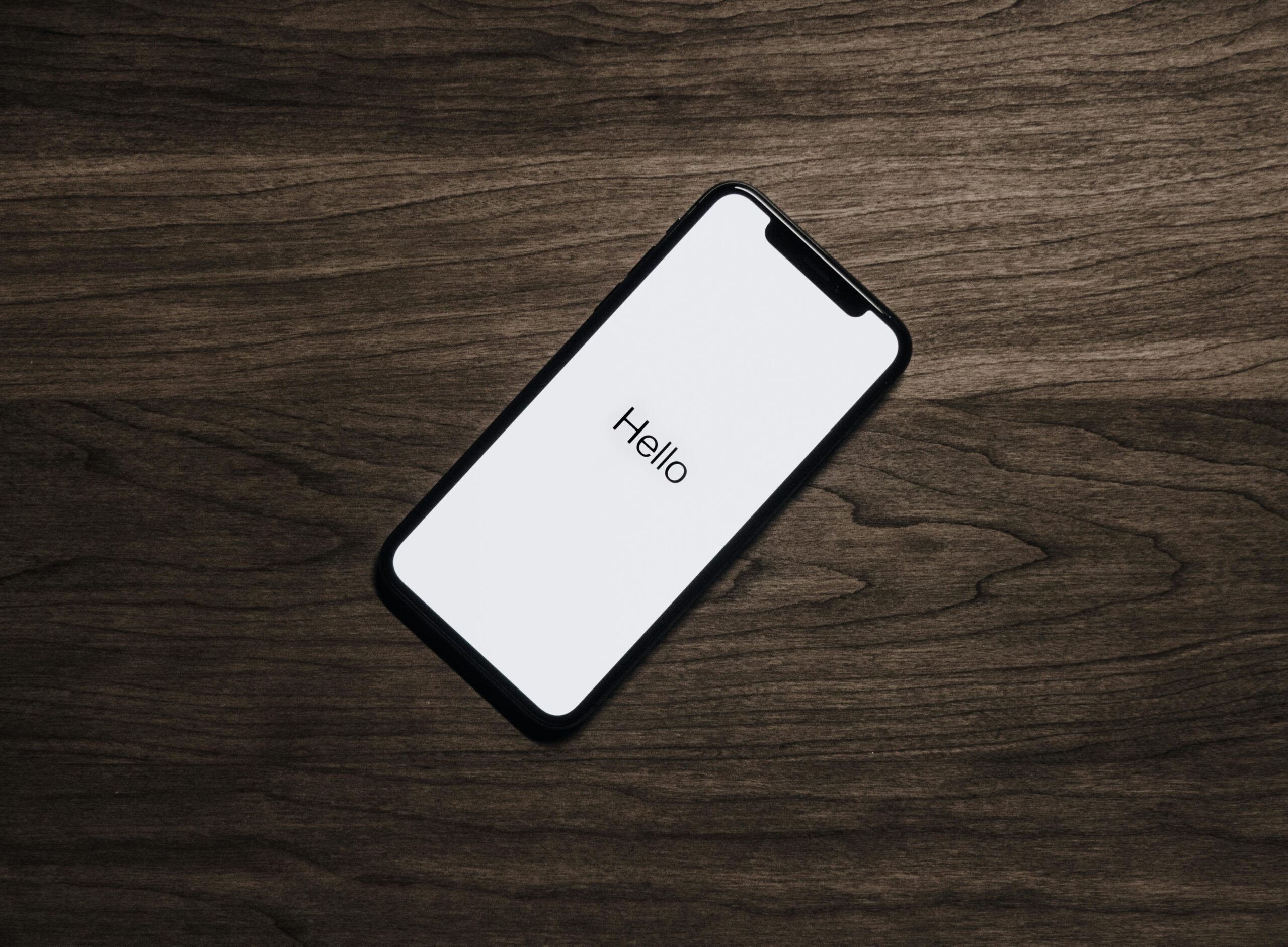 A smartphone displaying 'Hello' on a wooden surface, showcasing modern technology.