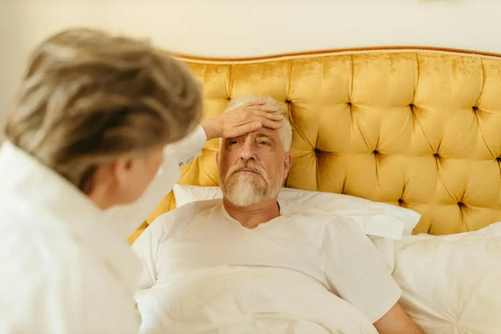 Elderly man in bed receiving care from a woman at home.