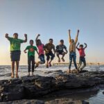 Group of kids joyfully jumping on rocks by the seaside. Fun and playful moment captured outdoors.