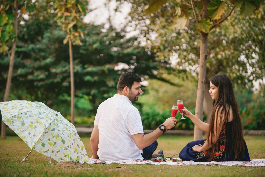 Couple enjoying a romantic picnic outdoors with drinks in a Delhi park.