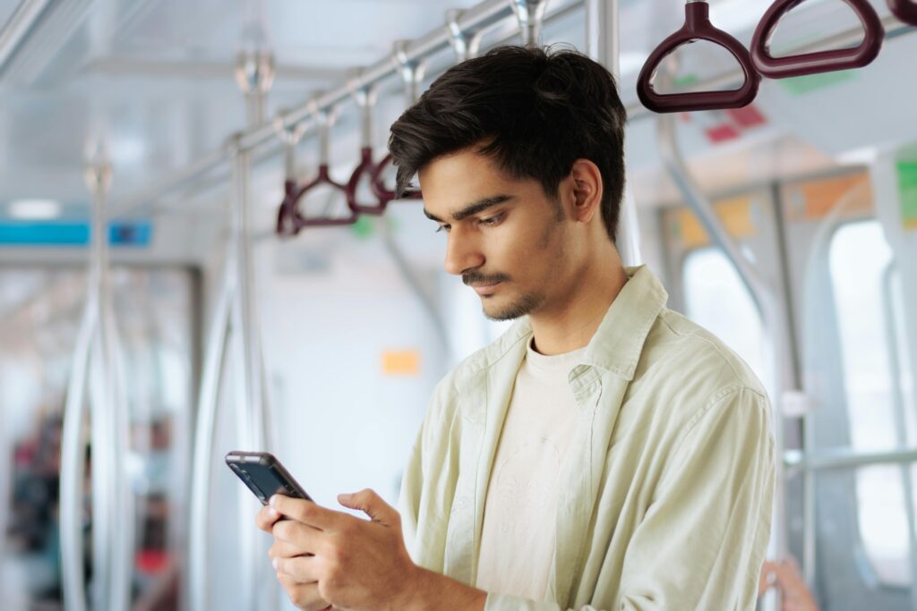 A young man using his smartphone while traveling on public transport.