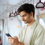 A young man using his smartphone while traveling on public transport.