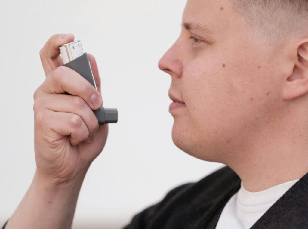 Close-up of an adult using an inhaler for asthma management.