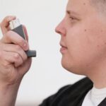 Close-up of an adult using an inhaler for asthma management.