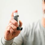 Middle-aged man using an inhaler to manage respiratory issues indoors.