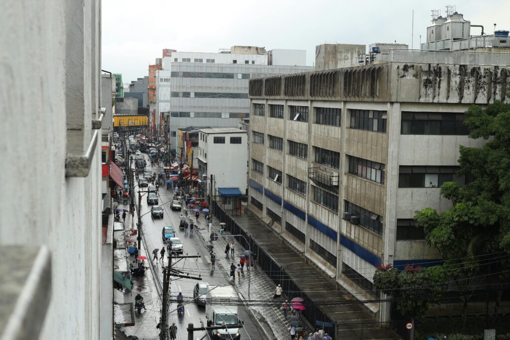 Street view of a bustling city under rain, showcasing diverse pedestrians and urban life.