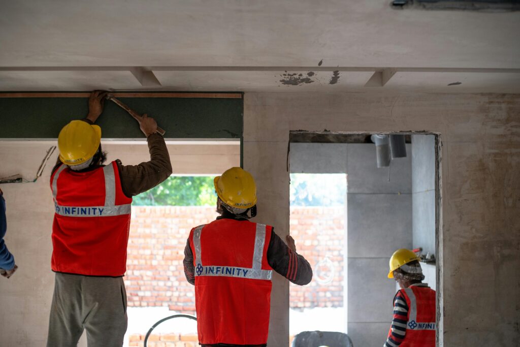 Construction workers renovating interior space in Delhi with safety gear and tools.