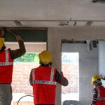 Construction workers renovating interior space in Delhi with safety gear and tools.