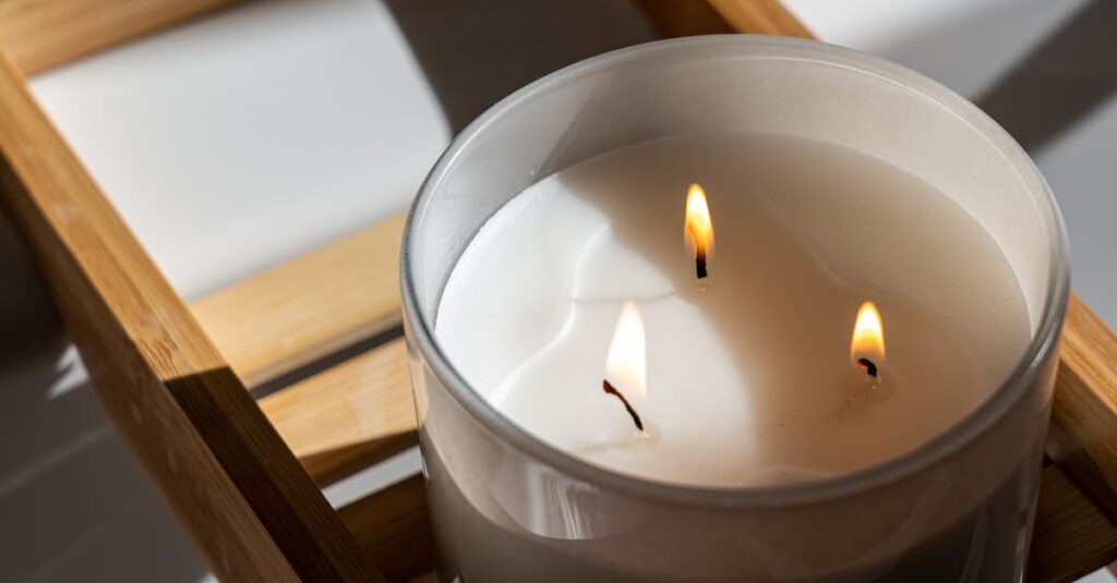 Elegant three-wick candle with a warm glow on a wooden tray, perfect for a tranquil ambiance.