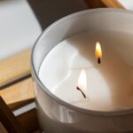 Elegant three-wick candle with a warm glow on a wooden tray, perfect for a tranquil ambiance.