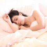 A serene woman sleeping comfortably on a bed with soft light.