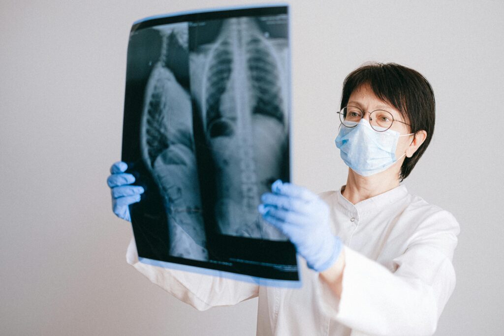 Doctor in protective gear examining chest x-ray for diagnosis.