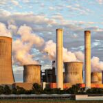 View of a power plant with smoke emissions under a cloudy sky, depicting industrial energy production.