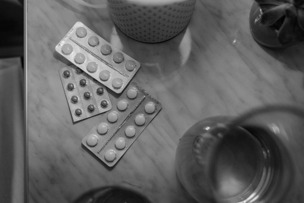 Monochrome image showing medication blisters on a table with soft lighting.