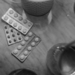 Monochrome image showing medication blisters on a table with soft lighting.