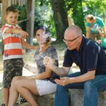 A family enjoying a sunny day at the park, capturing casual moments and interactions.
