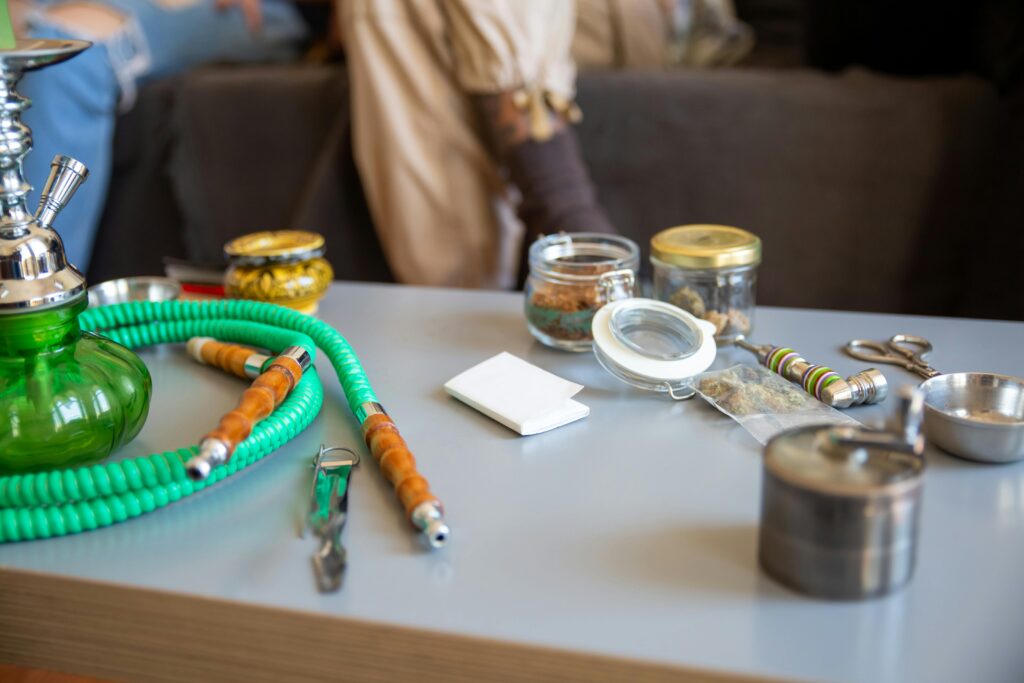 Close-up of a hookah and assorted jars on a table, showcasing recreational use of shisha accessories.