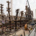 A bustling construction site with towering steel frameworks and cranes under a cloudy sky.